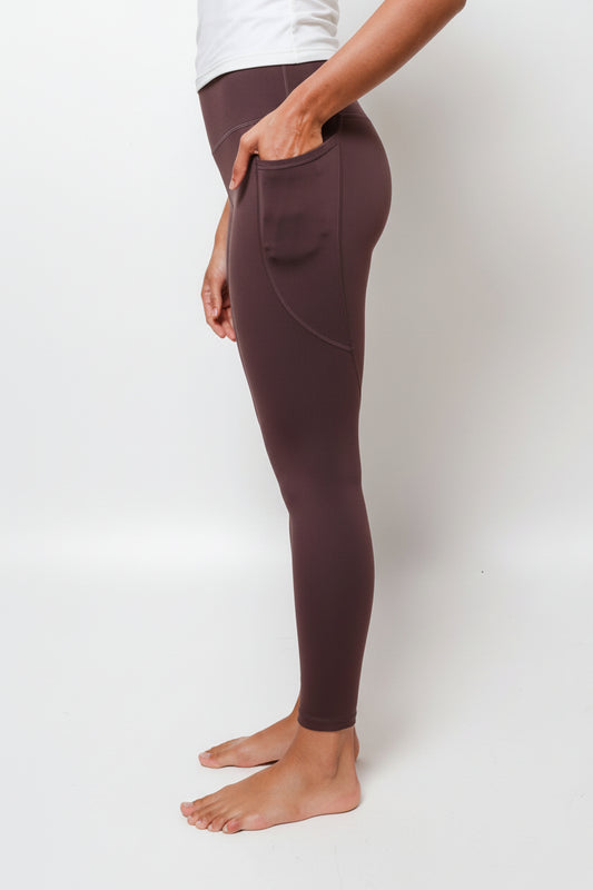Person wearing brown leggings on a white background