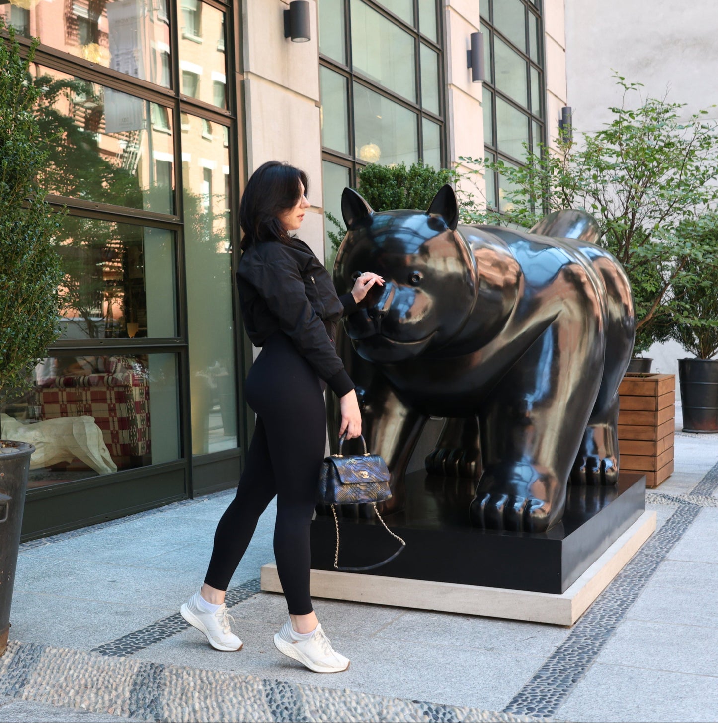 Woman standing next to a large dog statue in an urban setting