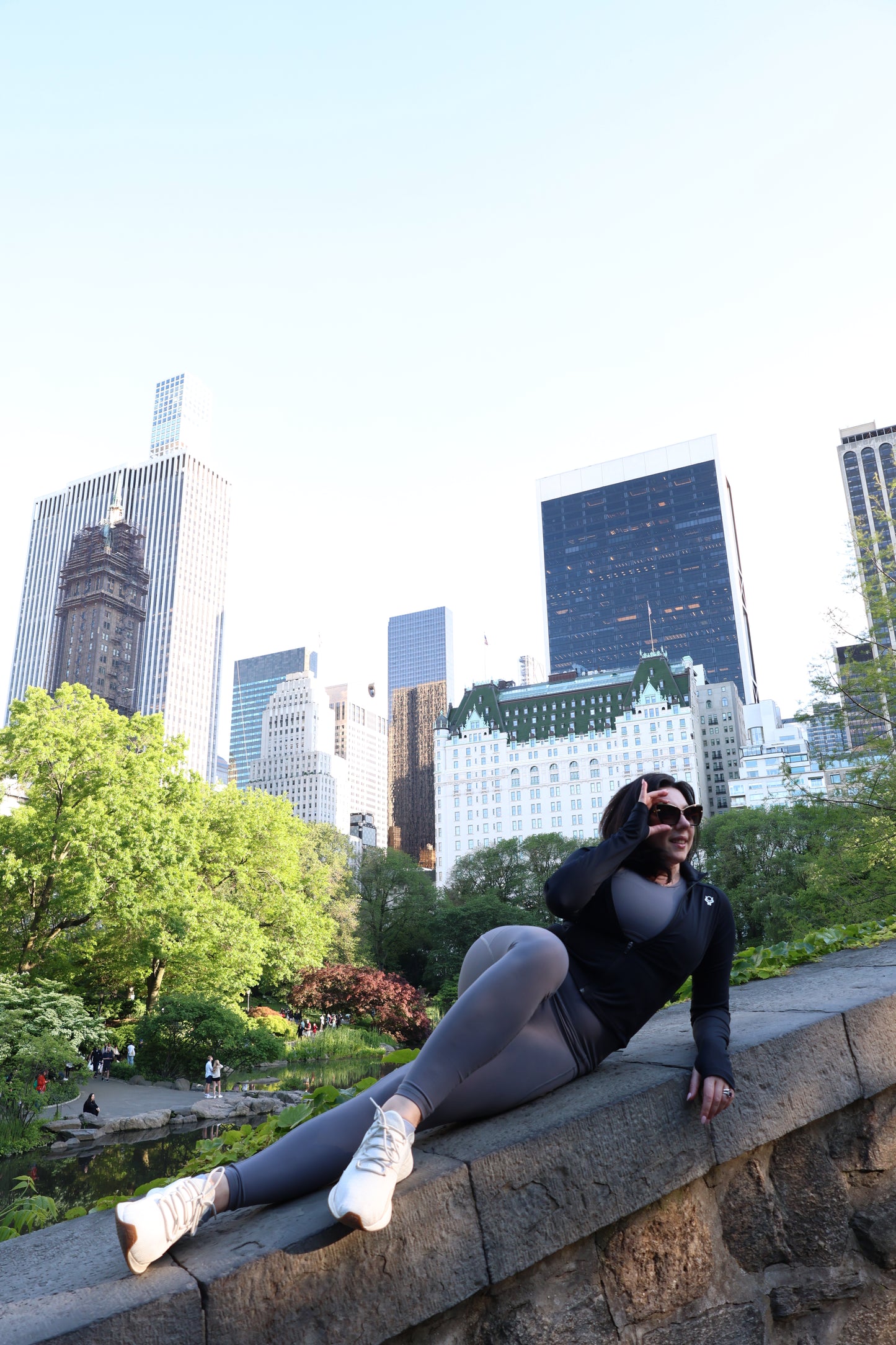 Person in athletic wear leaning against a stone wall with city skyline in the background