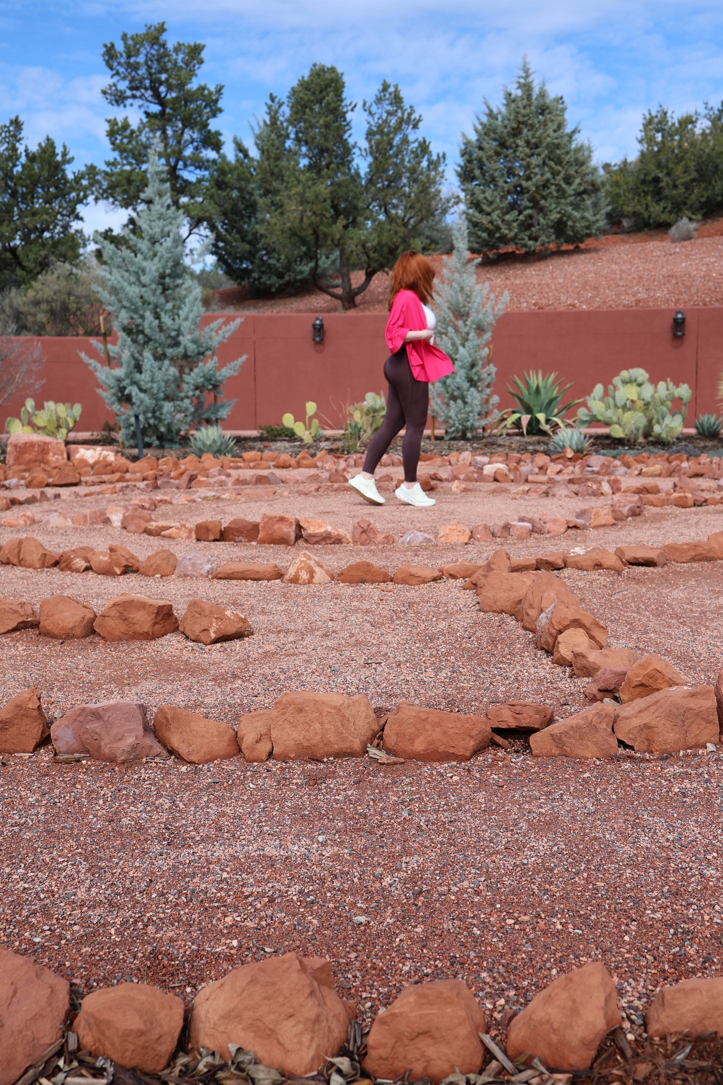 Person wearing Past Life Attire's Shot of Espresso Leggins, Cloud Soft Top and Cactus Flower Versatile Wrap walking on a stone path with trees and red rock in the background
