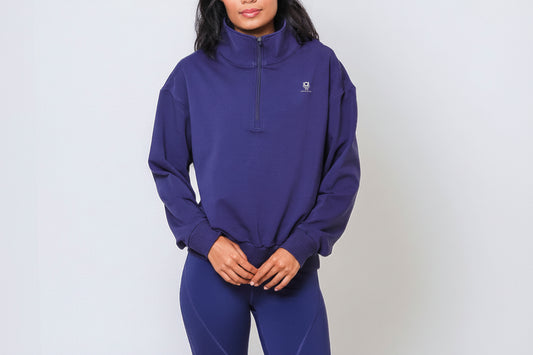 Person wearing a navy blue half zip pullover with a small Past Life Attire logo in white on a light gray background