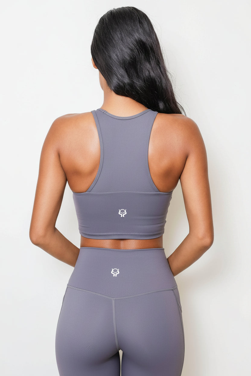 Person wearing a gray sports bra and leggings set on a white background