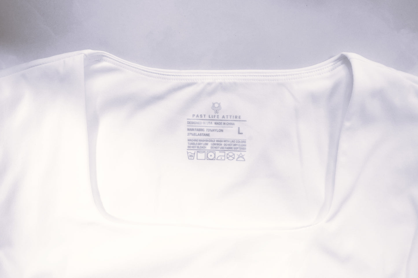 White square neck top with Past Life Attire silicon stamped seamless logo on the inside of the top