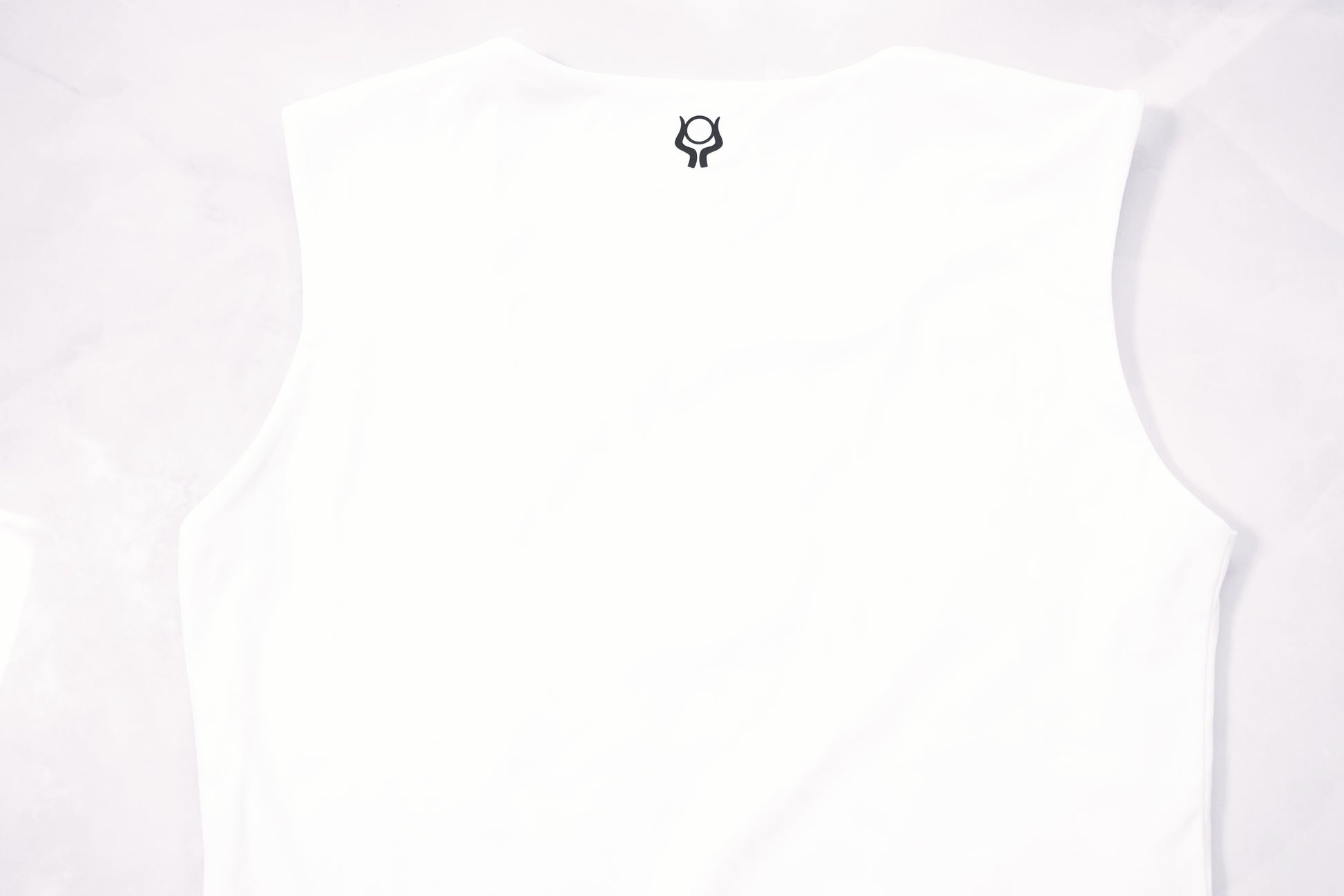 Soft cream sleeveless top with Past Life Attire brand logo on a marble white background